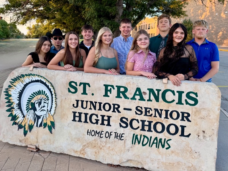 Five boys and five girls stand behind the school sign, as is tradition.